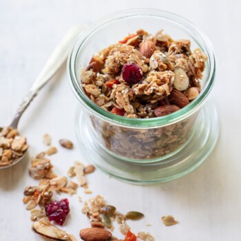 A jar of granola that contains whole almonds, oats, and dried cranberries.