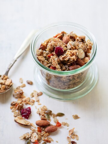 A jar of granola that contains whole almonds, oats, and dried cranberries.