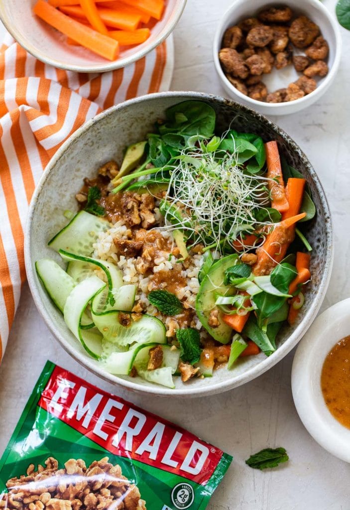 Gray bowl with chopsticks, full of rice salad with avocado, cucumber, carrots and walnut sauce.