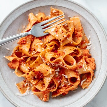 Pappardelle pasta noodles with red sauce in a bowl with a fork.