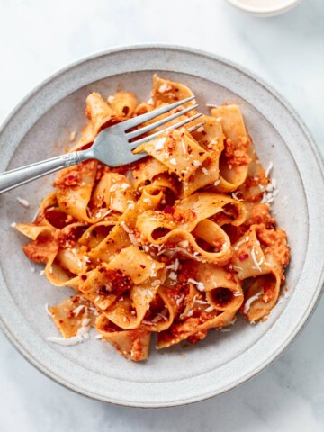 Pappardelle pasta noodles with red sauce in a bowl with a fork.