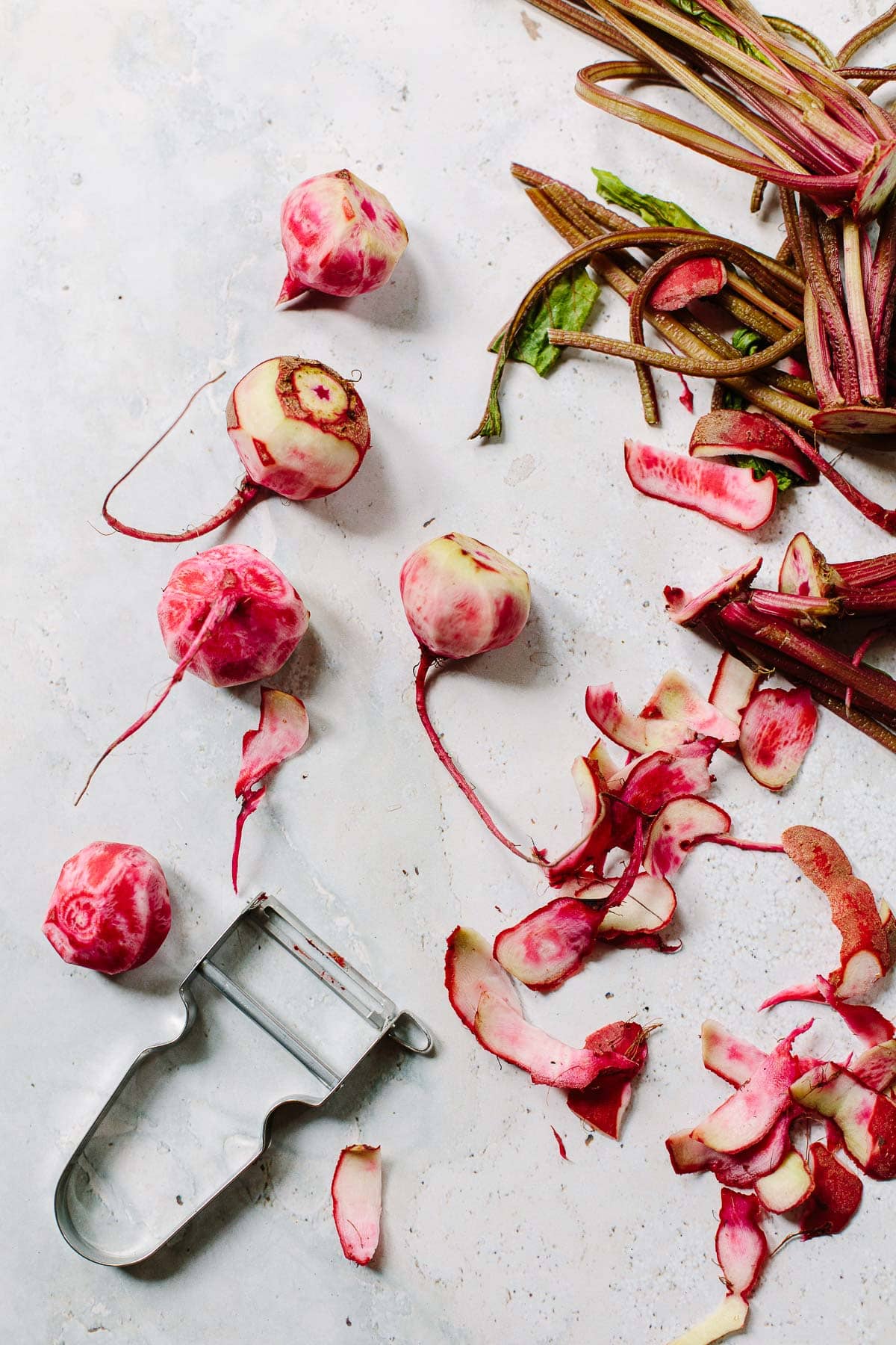 An image of peeled Chioggia beets with a metal vegetable peeler.