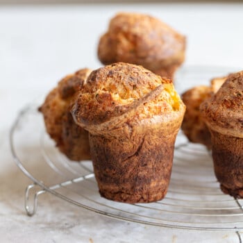 Tall, puffy baked Parmesan popovers arranged on a metal rack.