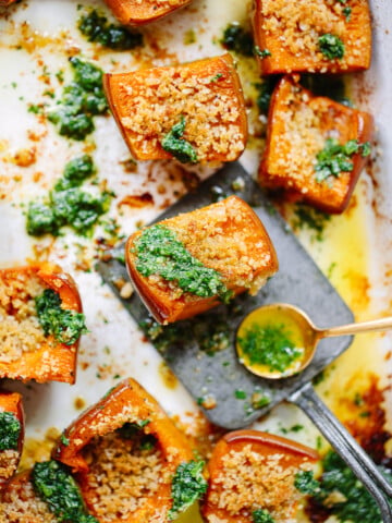 Chunks of roasted honey nut squash with green herb sauce spooned on top.