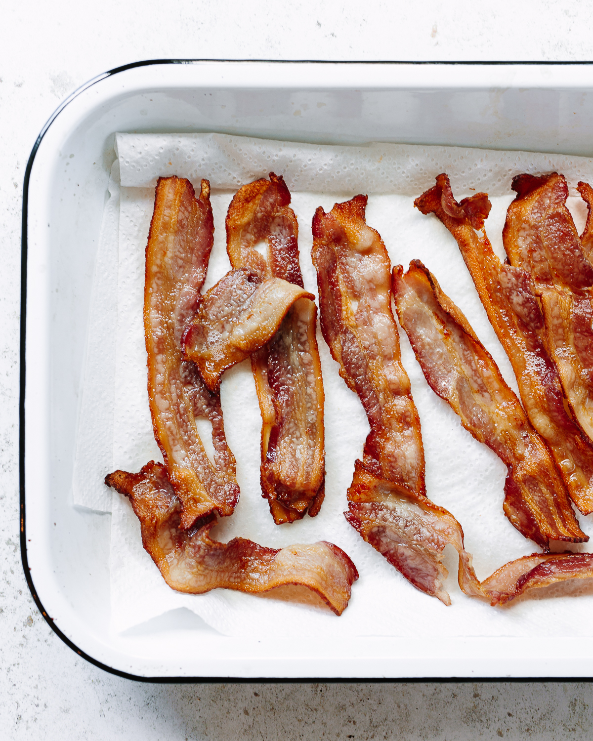 Photo of cooked bacon lined up on baking tray.