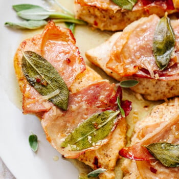 A close-up picture of cooked chicken breast with sage and prosciutto.