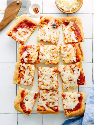 Rectangular slices of cheese pizza on a cutting board.