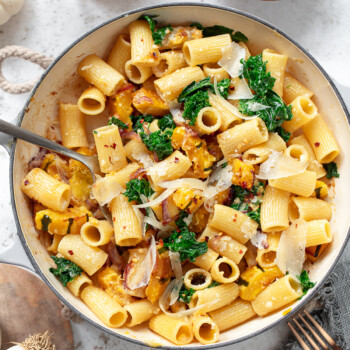 Rigatoni pasta in a serving pan with delicata squash sauce, kale and cheese.