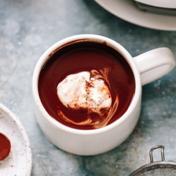A cup of hot chocolate with soft whipped cream swirled on top.