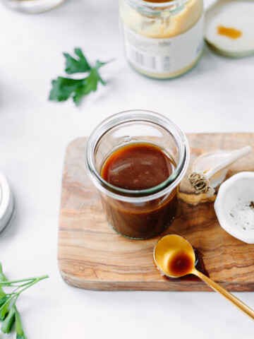 Balsamic vinaigrette in a glass jar, set on top of a small board..