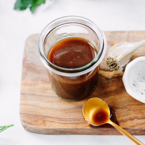 Balsamic vinaigrette in a glass jar, set on top of a small board.