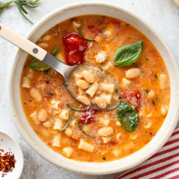 White bean soup in a bowl, with a spoon dipping into it.