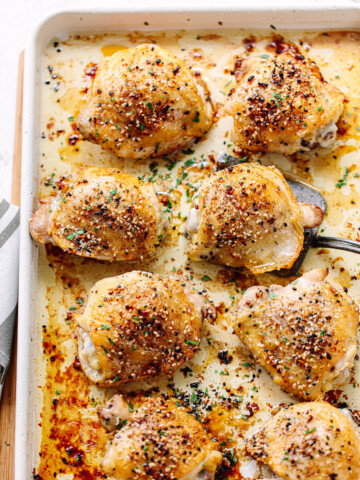 Crisp-skinned roasted chicken thighs on a sheet pan.