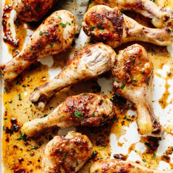 Juicy browned, spice-rubbed chicken legs on a white baking sheet.