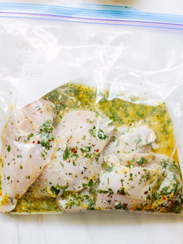 Boneless, skinless chicken breasts in a freezer bag, marinating in an herb and olive oil mixture.