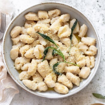 Ricotta gnocchi with Parmesan cheese and fried sage leaves in a serving bowl.