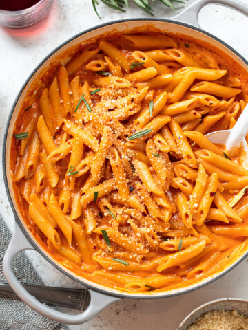 Penne pasta with creamy tomato-vodka gin sauce in a white skillet.