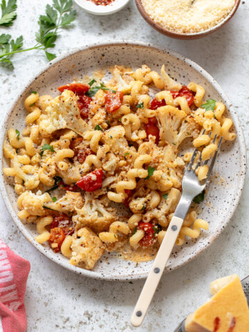 Gemelli pasta with roasted cauliflower sauce on a serving plate, with a fork on the side.