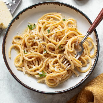 Cacio e pepe pasta in a serving bowl, with a fork resting on the side.