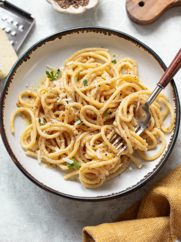 Cacio e pepe pasta in a serving bowl, with a fork resting on the side.