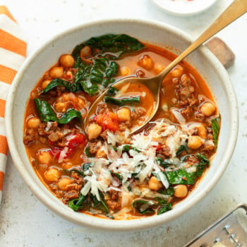 Chorizo chickpea stew garnished with shredded cheese in a serving bowl.