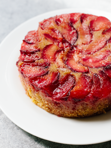 An unsliced upside down plum cake on a plate.