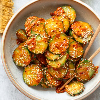 Spicy cucumber salad tossed with chili oil and peanut butter dressing served in a bowl.