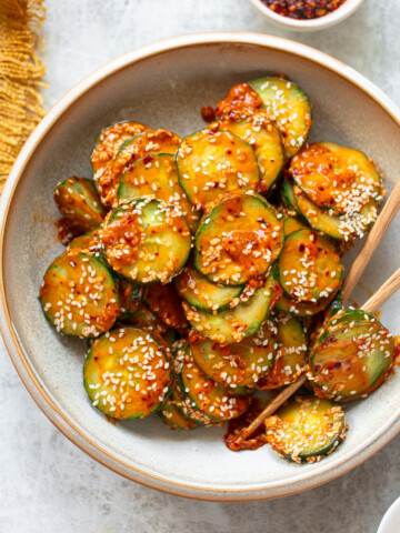 Spicy cucumber salad tossed with chili oil and peanut butter dressing served in a bowl.