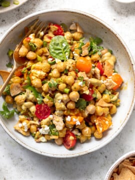 Chickpea salad mixed with sliced tomatoes, cilantro and feta cheese in a serving bowl.