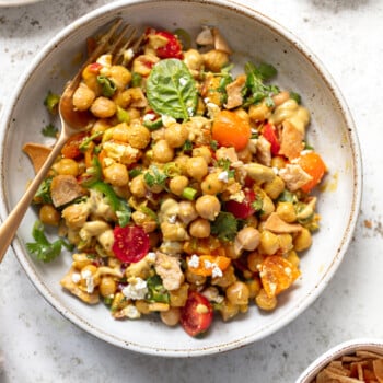 Chickpea salad mixed with sliced tomatoes, cilantro and feta cheese in a serving bowl.