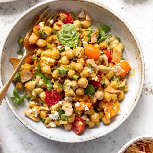 Chickpea salad mixed with sliced tomatoes, cilantro and feta cheese in a serving bowl.
