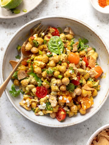 Chickpea salad mixed with sliced tomatoes, cilantro and feta cheese in a serving bowl.