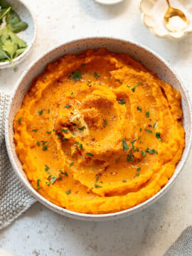 Butternut squash puree in a serving bowl, with a topping of melted butter.