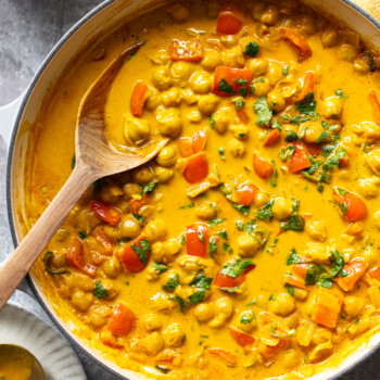 Creamy, golden chickpeas in a coconut milk sauce in a skillet with bell peppers and cilantro.