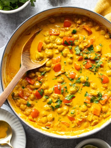 Creamy, golden chickpeas in a coconut milk sauce in a skillet with bell peppers and cilantro.