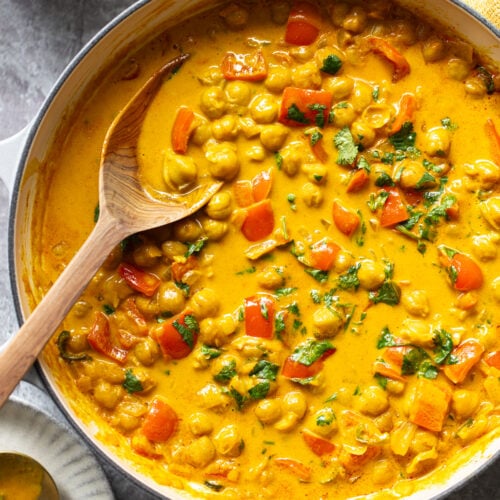 Creamy, golden chickpeas in a coconut milk sauce in a skillet with bell peppers and cilantro.