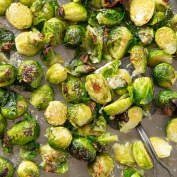 Roasted Brussels sprouts on a sheet pan, with crisp brown edges and melted Parmesan cheese.