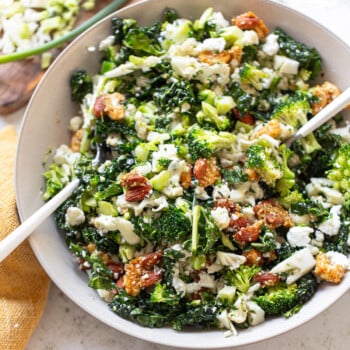 Broccoli and cauliflower tossed in a salad bowl with almonds and feta cheese crumbles.