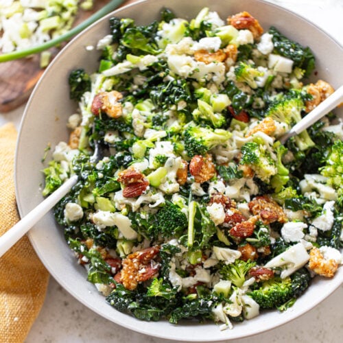 Broccoli and cauliflower tossed in a salad bowl with almonds and feta cheese crumbles.